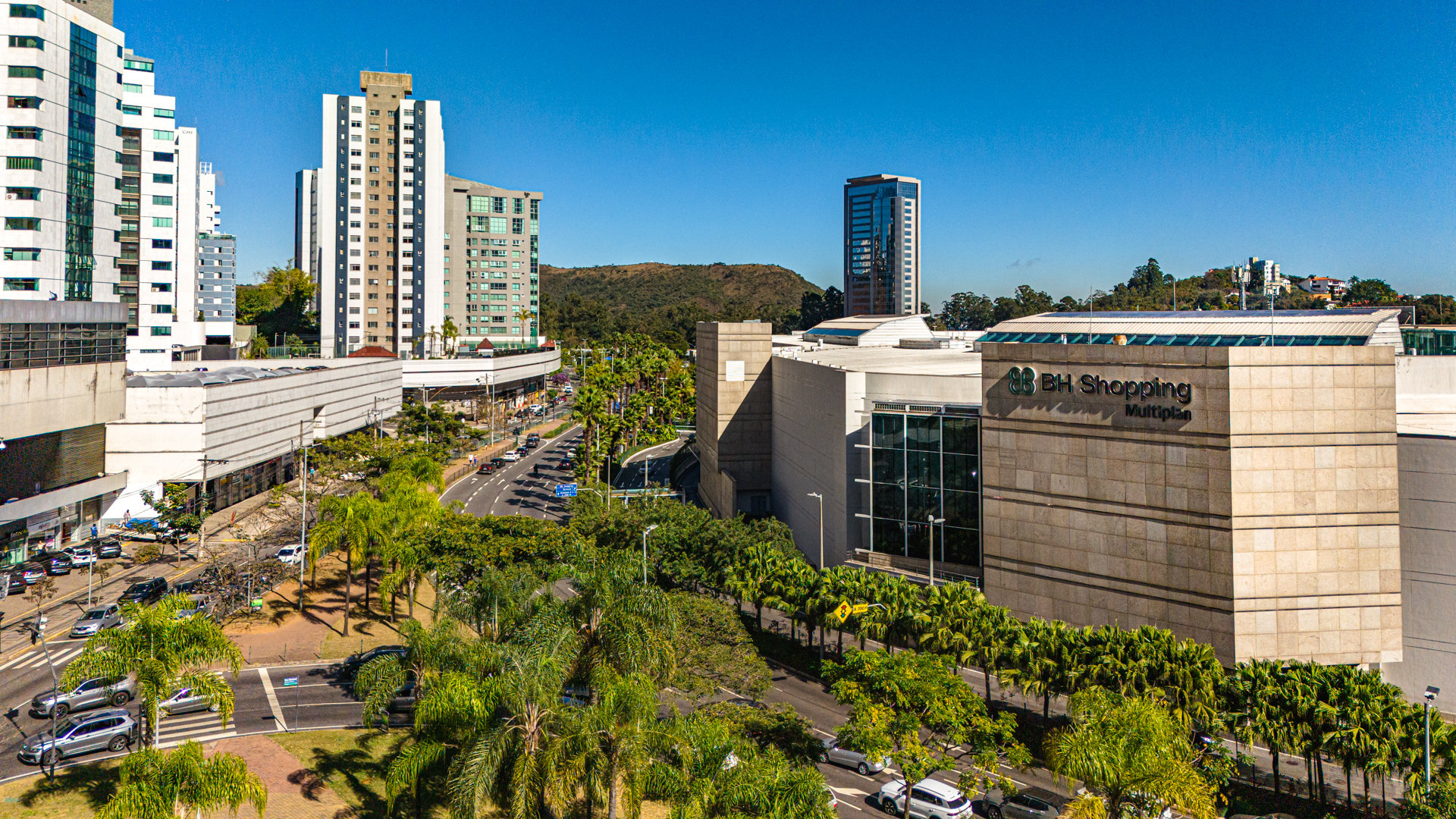 Daytime aerial of BH Shopping mall in Belo Horizonteโs Belvedere district, with palm-lined Raja Gabaglia Avenue and surrounding residential towers.